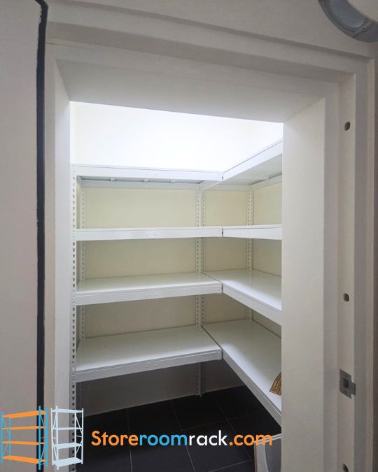 L-shaped rack inside an HDB household shelter with its shelves running unbroken around the corner, seen through the open blast door