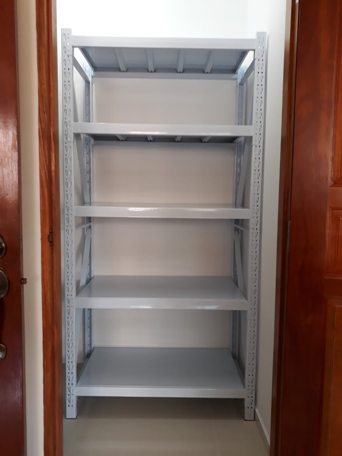 Beige metal boltless storage rack installed floor to ceiling in an HDB household shelter